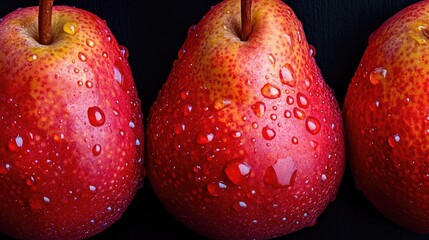 A close-up of three red pears with water droplets glistening on their smooth skin, arranged in a neat row