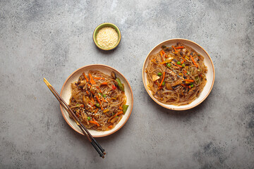 Traditional Korean noodles, two bowls of japchae. A dish featuring sweet potato noodles stir fried with a colorful vegetables and savory meat