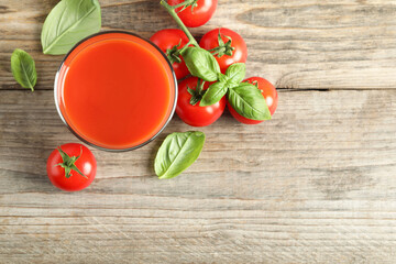 Wall Mural - Tasty tomato juice in glass, basil leaves and fresh vegetables on wooden table, flat lay. Space for text