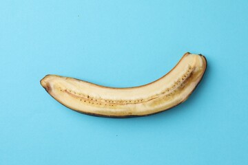 Canvas Print - Half of overripe banana on light blue background, top view