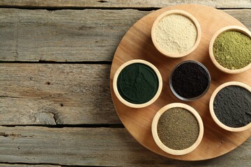 Wall Mural - Different superfood powders in bowls on wooden table, top view. Space for text