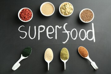 Wall Mural - Word Superfood and different healthy powders on black table, flat lay