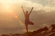 © Rob Wilkinson - woman doing a tree pose yoga position outdoors on rocks at sunrise, sunset.