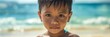 © nopommajun - A young boy stands on a beach with the ocean behind him, wet hair and serious expression, embodying a moment of quiet reflection.