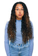 © Krakenimages.com - Young hispanic woman with curly hair wearing casual clothes puffing cheeks with funny face. mouth inflated with air, crazy expression.