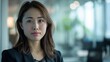 © nopommajun - A confident woman dressed in business attire stands with poise in an office setting, symbolizing professionalism and success in a corporate environment.