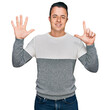 © Krakenimages.com - Handsome young man wearing casual winter sweater showing and pointing up with fingers number seven while smiling confident and happy.