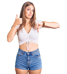 Wall Mural - Young beautiful blonde woman wearing casual white tshirt doing thumbs up and down, disagreement and agreement expression. crazy conflict