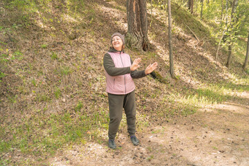 woman in casual attire gesturing near a forested area during daytime