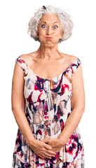 senior grey-haired woman wearing casual clothes puffing cheeks with funny face. mouth inflated with 