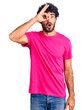 © Krakenimages.com - Handsome young man with curly hair and bear wearing casual pink tshirt doing ok gesture shocked with surprised face, eye looking through fingers. unbelieving expression.