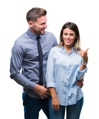 Wall Mural - Young workers business couple over isolated background smiling with happy face looking and pointing to the side with thumb up.