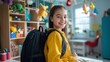 © Ailee Tian - A happy young girl with a school bag stands at the desk in her room.