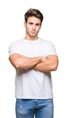 Young handsome man wearing white t-shirt over isolated background skeptic and nervous, disapproving expression on face with crossed arms. Negative person.