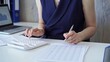 © volha_r - Businesswoman with dark blue dress is using white calculator and taking notes in her office. Taxes and audit in business
