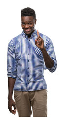 Wall Mural - Young african american man wearing blue shirt showing and pointing up with finger number one while smiling confident and happy.