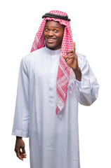 Wall Mural - Young arabic african man wearing traditional keffiyeh over isolated background pointing finger up with successful idea. Exited and happy. Number one.