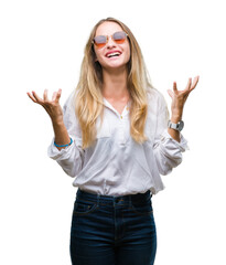 Sticker - Young beautiful blonde woman wearing sunglasses over isolated background crazy and mad shouting and yelling with aggressive expression and arms raised. Frustration concept.