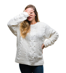 Sticker - Young beautiful blonde woman wearing winter sweater and sunglasses over isolated background peeking in shock covering face and eyes with hand, looking through fingers with embarrassed expression.