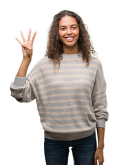 Poster - Beautiful young hispanic woman wearing stripes sweater showing and pointing up with fingers number four while smiling confident and happy.