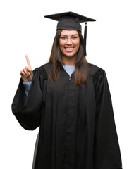 Poster - Young hispanic woman wearing graduated cap and uniform showing and pointing up with finger number one while smiling confident and happy.