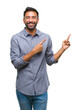 © Krakenimages.com - Adult hispanic man over isolated background smiling and looking at the camera pointing with two hands and fingers to the side.