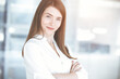 © volha_r - Beautiful female specialist with arms crossed standing in sunny office and smiling charmingly. Business people concept