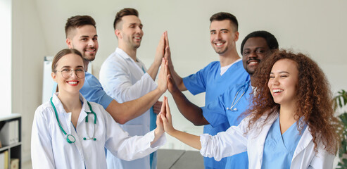 Group of doctors putting hands together in clinic. Unity concept