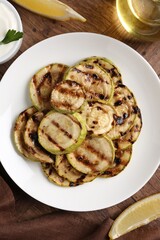 Wall Mural - Tasty grilled courgette slices served on wooden table, flat lay