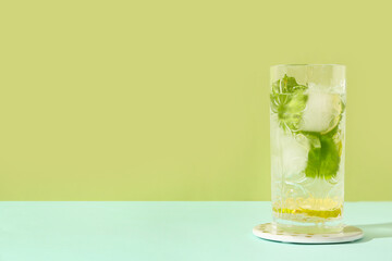 Wall Mural - Glass of fresh mojito on blue table against green background