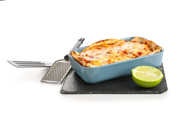 Wall Mural - Baking dish with tasty enchilada, lime and kitchen utensils on white background