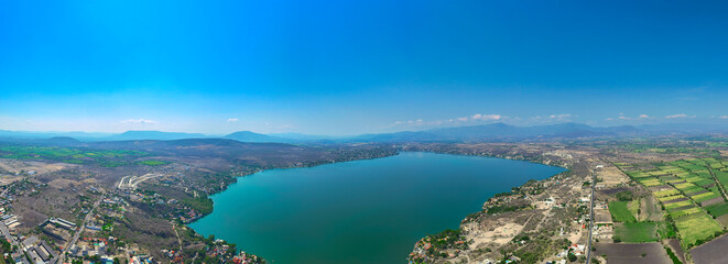 Aerial view of Lake Tequesquitengo on a sunny morning: the turquoise blue of the lake and the distant mountains create a beautiful landscape.