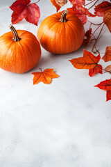 Wall Mural - Vertical fall background with orange pumpkins and fall leaves on a white concrete surface