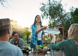 Wall Mural - Food, friends and dinner party on backyard patio with happy people and conversation at labor day lunch. Holiday, reunion and meal outside of home with salad, plates and care of host at social event