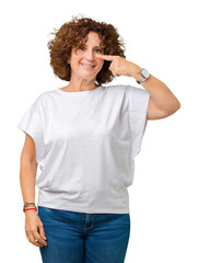 Wall Mural - Beautiful middle ager senior woman wearing white t-shirt over isolated background Pointing with hand finger to face and nose, smiling cheerful