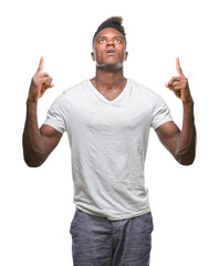 Wall Mural - Young african american man over isolated background amazed and surprised looking up and pointing with fingers and raised arms.