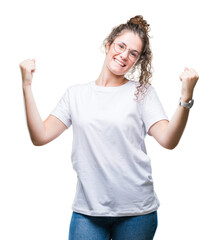 Sticker - Beautiful young brunette curly hair girl wearing glasses over isolated background celebrating surprised and amazed for success with arms raised and open eyes. Winner concept.