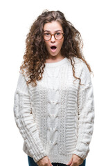 Sticker - Beautiful brunette curly hair young girl wearing winter sweater over isolated background afraid and shocked with surprise expression, fear and excited face.