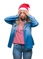 Wall Mural - Beautiful young blonde woman wearing christmas hat over isolated background suffering from headache desperate and stressed because pain and migraine. Hands on head.