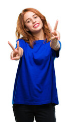 Canvas Print - Young beautiful woman over isolated background smiling looking to the camera showing fingers doing victory sign. Number two.