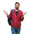 © Krakenimages.com - Adult hispanic student man wearing headphones and backpack over isolated background clueless and confused expression with arms and hands raised. Doubt concept.