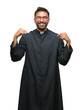 © Krakenimages.com - Adult hispanic catholic priest man over isolated background looking confident with smile on face, pointing oneself with fingers proud and happy.