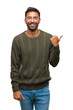 © Krakenimages.com - Adult hispanic man wearing winter sweater over isolated background smiling with happy face looking and pointing to the side with thumb up.