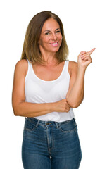 Wall Mural - Beautiful middle age casual adult woman over isolated background with a big smile on face, pointing with hand and finger to the side looking at the camera.