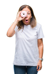 Poster - Middle age hispanic woman eating pink donut over isolated background scared in shock with a surprise face, afraid and excited with fear expression