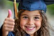 © At My Hat - Smiling girl gives thumbs up. A happy graduate gives a thumbs up, perfect for education and achievement themes.