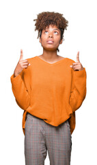 Wall Mural - Beautiful young african american woman over isolated background amazed and surprised looking up and pointing with fingers and raised arms.