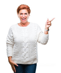 Poster - Atrractive senior caucasian redhead woman wearing winter sweater over isolated background with a big smile on face, pointing with hand and finger to the side looking at the camera.