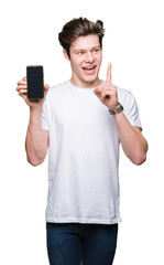 Wall Mural - Young man showing smartphone screen over isolated background surprised with an idea or question pointing finger with happy face, number one