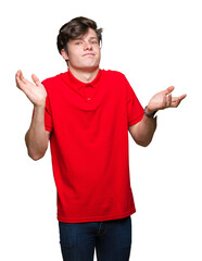 Wall Mural - Young handsome man wearing red t-shirt over isolated background clueless and confused expression with arms and hands raised. Doubt concept.